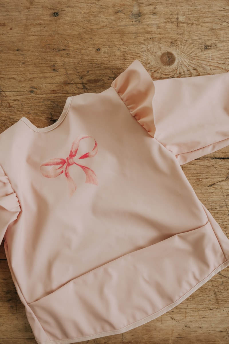 Elodie Details slab met lange mouwen Rosy Bow met waterafstotend voorpand, verkrijgbaar bij De Gele Flamingo.