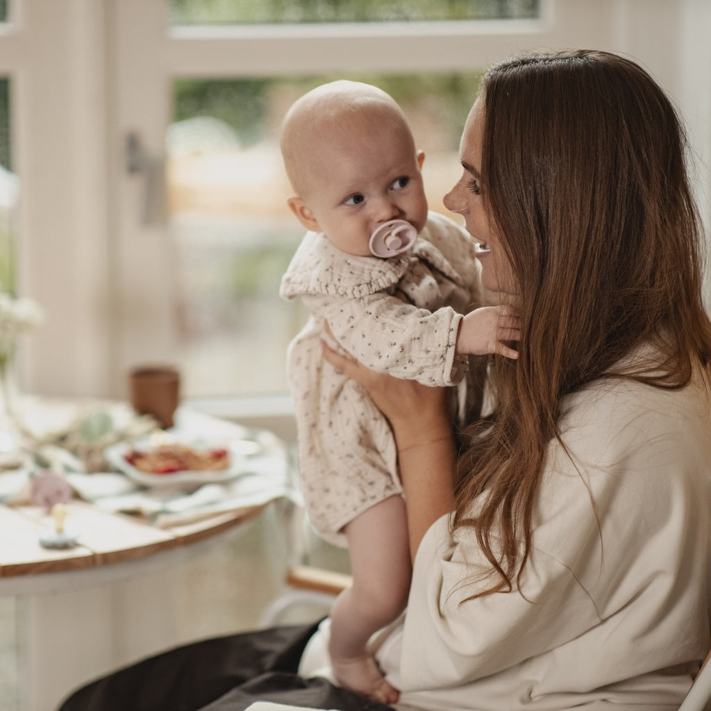 Frigg Mini Mocha fopspeen, baby met speen op de arm van mama