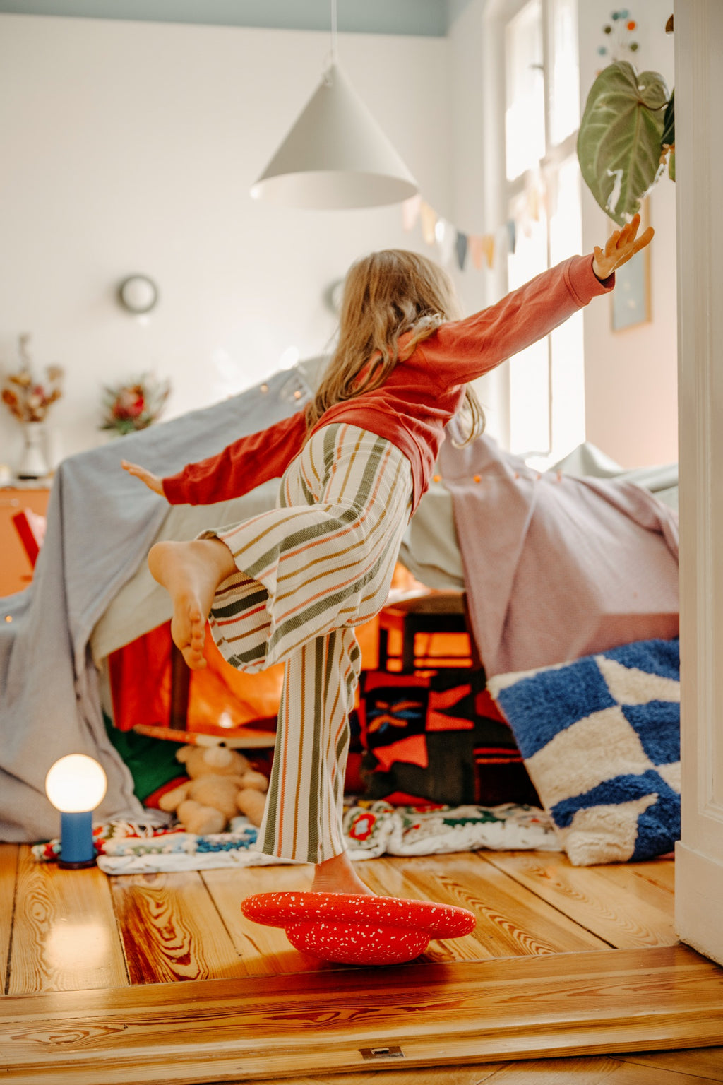 Stapelstein Winter Special Balance Board Red & Rose, kind balanceert op het bord in de woonkamer